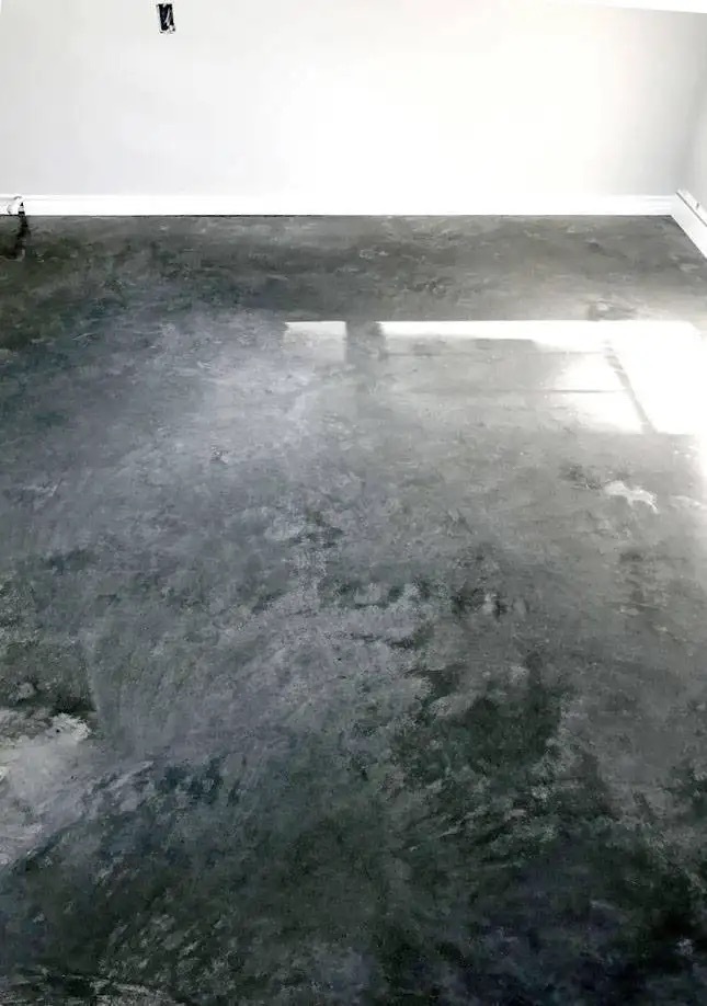 This image shows a man applying epoxy paint on the floor.